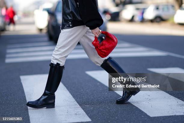 Guest wears rings, a black leather jacket with black suede sleeves , white leather pants, black riding boots, a red woven leather handbag, outside...