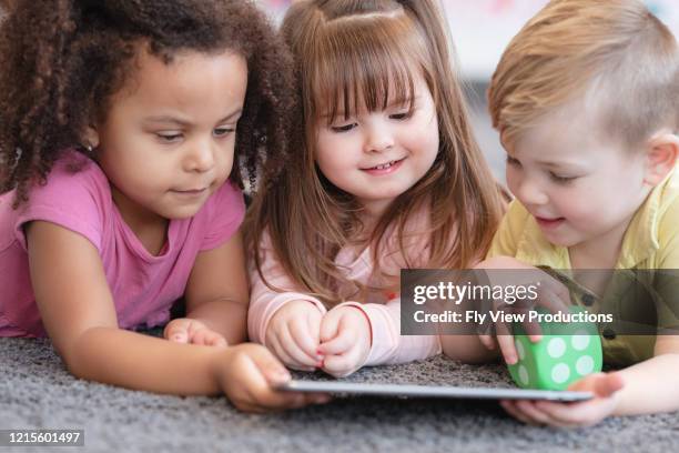 happy preschool students engaged with a tablet - development camp stock pictures, royalty-free photos & images