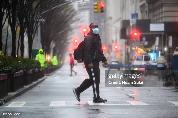 Person wears a protective face mask while walking in Park Avenue as part of NYC's "Open Streets", which closes some streets to vehicle traffic to...