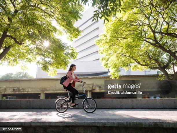 junge frau geht mit dem fahrrad zur arbeit - leben in der stadt stock-fotos und bilder