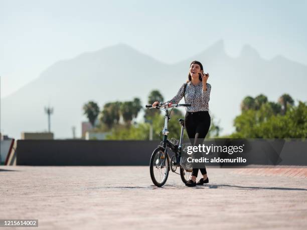 junge frau zu fuß mit dem fahrrad in der stadt und mit telefon - nuevo leon stock-fotos und bilder