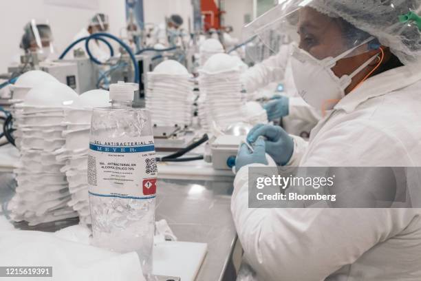 Bottle of hand sanitizer sits next to a worker assembling N95 masks at the High Technology in Air Filtration manufacturing facility in Xochimilco,...