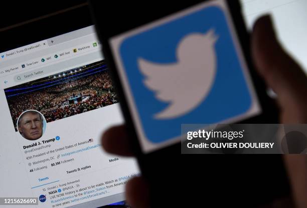 In this photo illustration, a Twitter logo is displayed on a mobile phone with President Trump's Twitter page shown in the background on May 27 in...