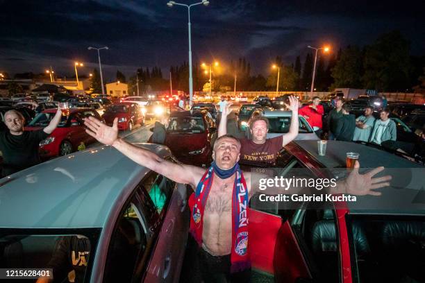 Fans cheer as they watch the Czech first division football match between FC Viktoria Plzen and AC Sparta Praha at a drive-in movie theater on May 27,...