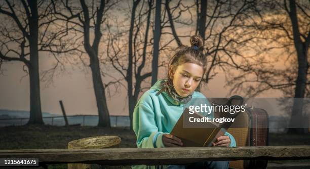 une fille lit un livre dans le soir - children oil lamp study photos et images de collection