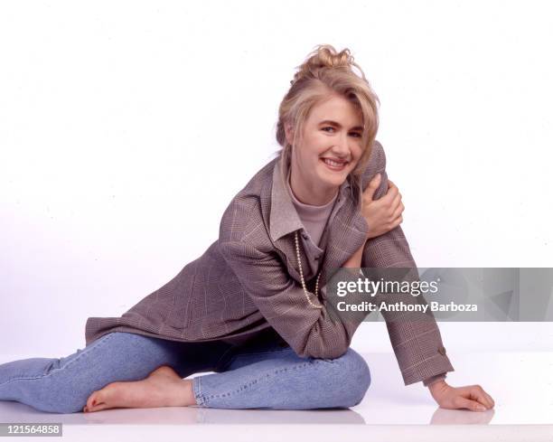 Portrait of American actress Laura Dern as she sits against a white background, 1990.