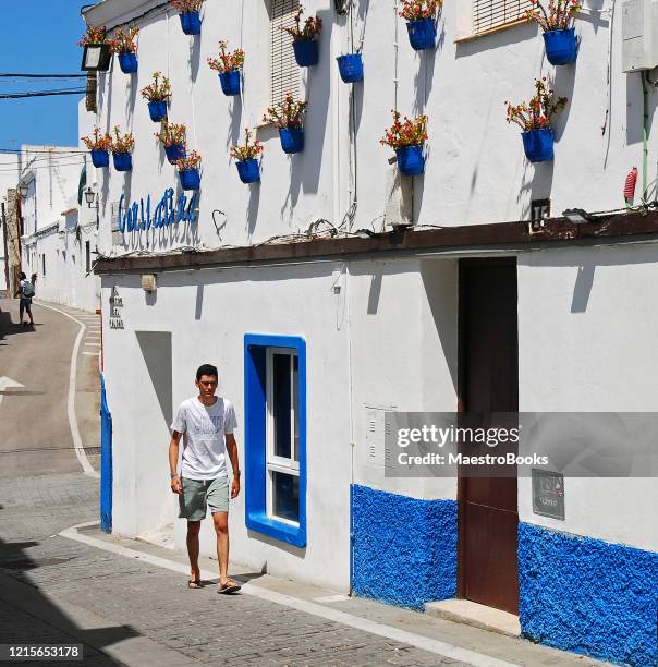 junger mann geht allein auf einer weiß getünchten straße in cadiz - tarifa stock-fotos und bilder