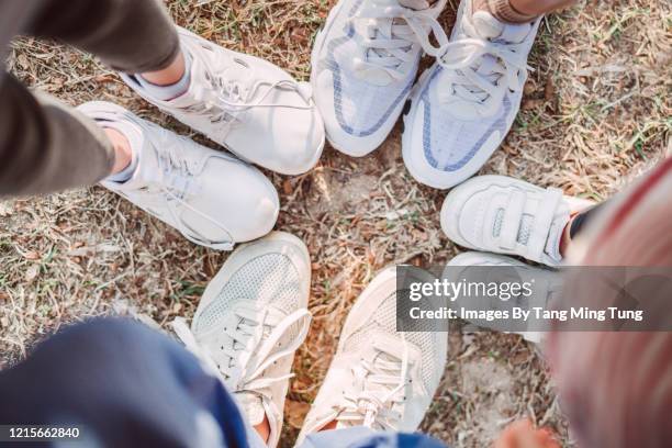 top view of a family of four wearing sneakers on lawn - white shoes stock-fotos und bilder