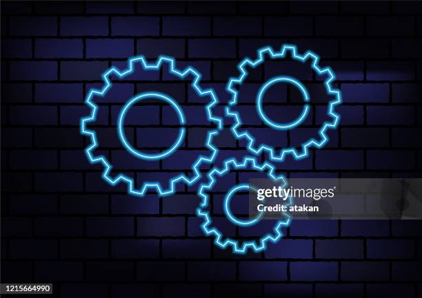gear shape blue neon light on dark brick wall - engine light stock illustrations