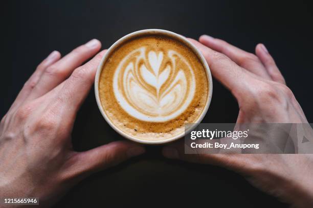 top view of human hand holding a cup of hot latte coffee on table before drink. - on top of stock pictures, royalty-free photos & images