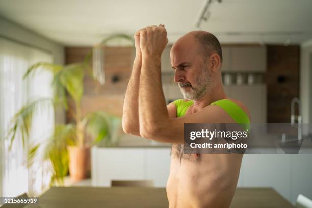 man with elastic therapeutic tapes on shoulders exercising during covid-19 curfew at home - kinesiotape stock pictures, royalty-free photos & images