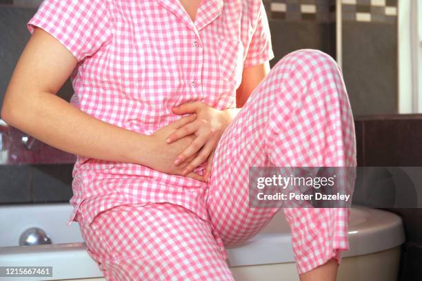 woman holding stomach in pain - endometriosis stock pictures, royalty-free photos & images