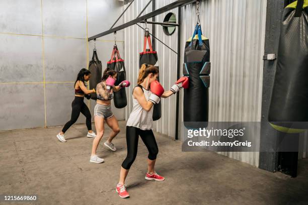 young female boxers working out with heavy bags at gym - boxing womens stock pictures, royalty-free photos & images