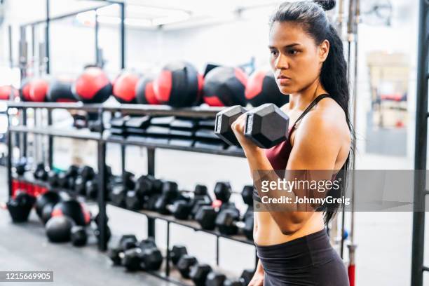 athlète féminin concentré soulevant l’haltère à la gymnastique - musculation des biceps photos et images de collection