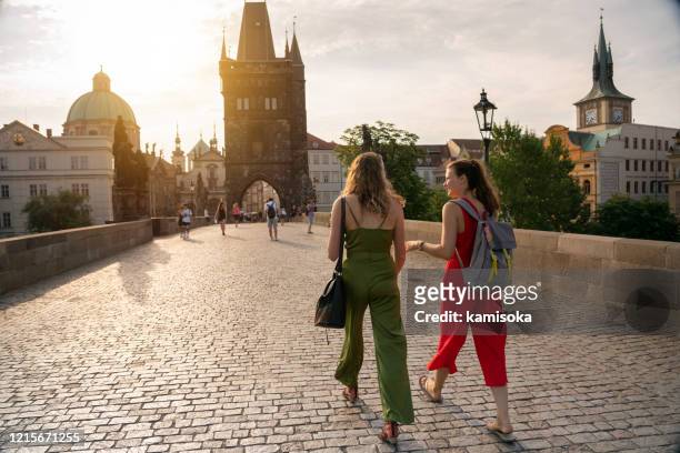 female friends on holiday walking on charles bridge in prague - prague stock pictures, royalty-free photos & images