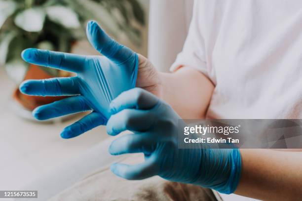 una femmina asiatica cinese che indossa i guanti chirurgici in lattice a casa prima del processo di pulizia - abbigliamento da lavoro foto e immagini stock