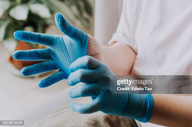 een aziatisch chinees wijfje dat haar latex chirurgische handschoenen thuis vóór het schoonmakensproces draagt - beschermende handschoen stockfoto's en -beelden