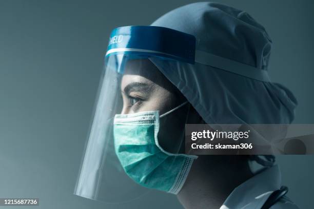 portrait asian female doctor wearing face shield and ppe suit and holding syringe for coronavirus outbreak or covid-19, concept of covid-19 quarantine - face shield stock-fotos und bilder