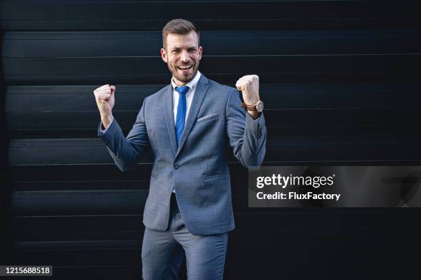 jubelnder geschäftsmann mit erhobenen armen feiert gute nachricht - fist celebrating stock-fotos und bilder