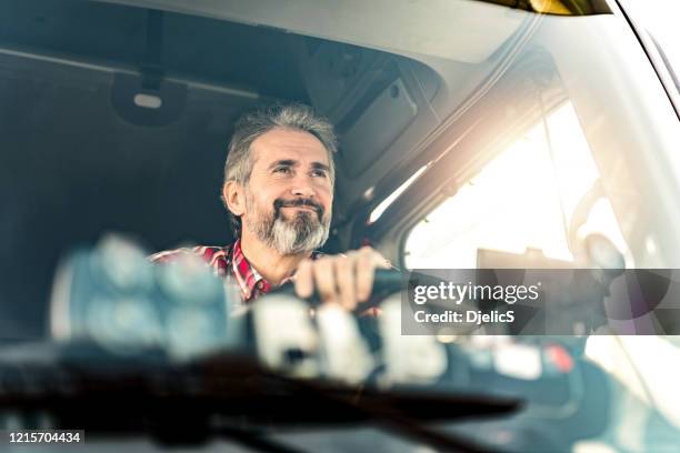 happy mature truck driver driving his truck on a sunny day. - truck cabin stock pictures, royalty-free photos & images