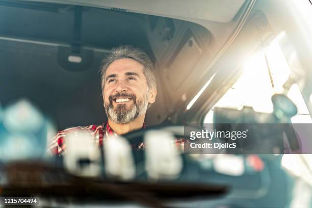 happy mature truck driver driving his truck to a warehouse. - truck driver stock pictures, royalty-free photos & images