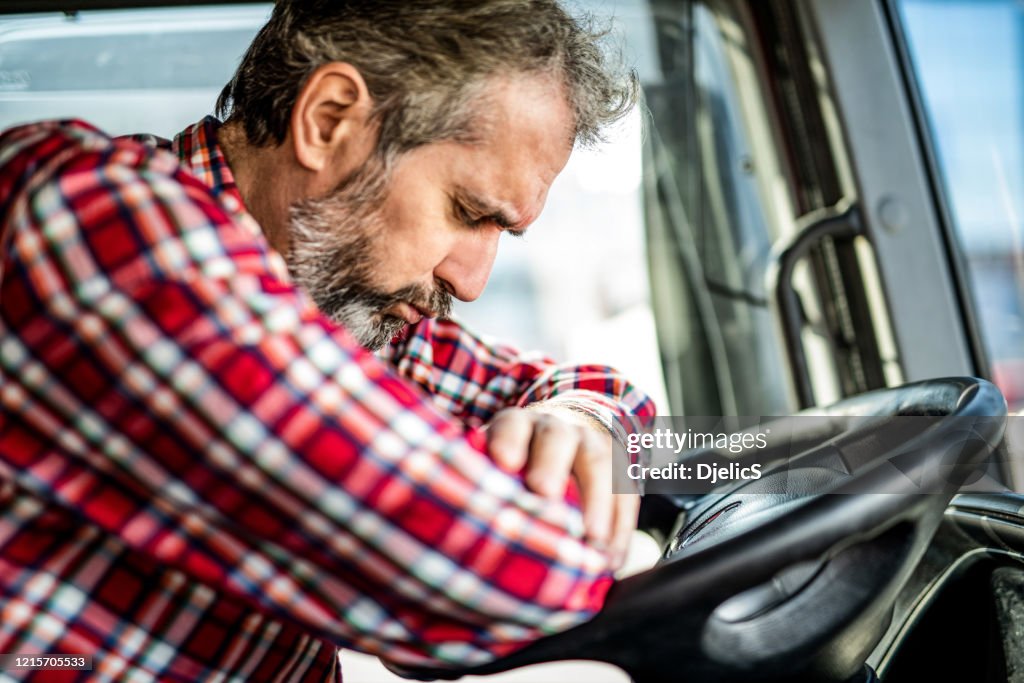 Tired mature truck driver waiting in traffic and contemplating about job problems.