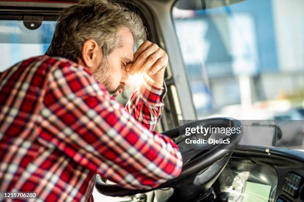 vermoeide rijpe vrachtwagenchauffeur die in verkeer wacht en over baanproblemen overweegt. - trucker stockfoto's en -beelden