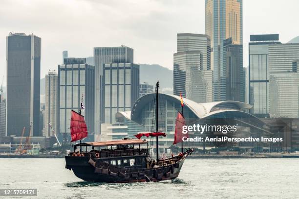 junk boat crossing hong kong harbor - hong kong junk boat stock-fotos und bilder