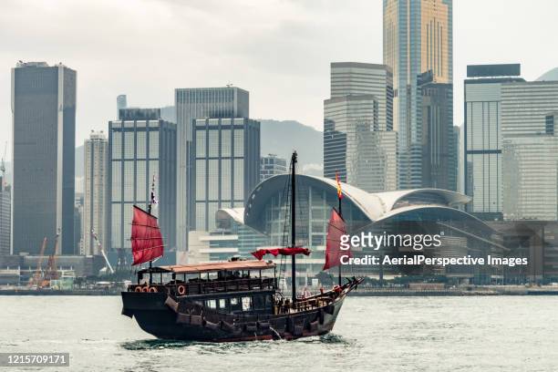 junk boat crossing hong kong harbor - wooden boat stock pictures, royalty-free photos & images