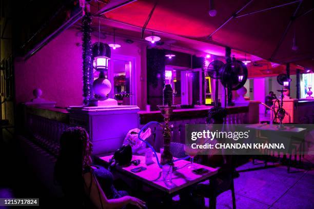 People have drinks and hookah on the patio of a restaurant on Ocean Drive in South Beach, Miami, on May 27 as Miami Beach reopens to business. - The...