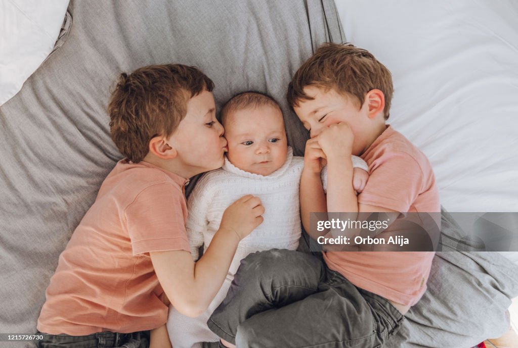 Brüder spielen mit Baby auf dem Bett