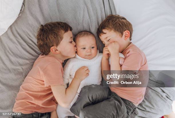 brüder spielen mit baby auf dem bett - bruder stock-fotos und bilder