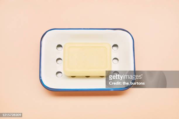 high angle view of an enamel soap dish and bar soap for washing hands on beige colored background - saboneteira imagens e fotografias de stock