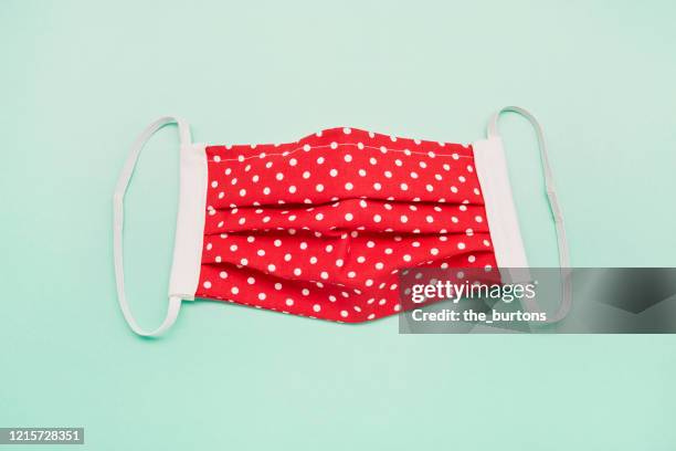 still life of a self made red face mask on green background, diy sewing project - cloth face mask foto e immagini stock