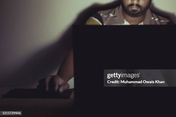 portrait of man using laptop in dark room - dark room foto e immagini stock