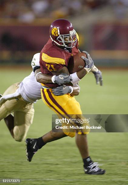 Tailback LenDale White of the University of Southern California fights the tackle of cornerback Robert Herbert of Colorado State University during...