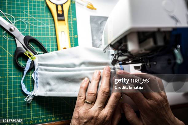 high angle view close-up of mature woman sewing protective face masks during coronavirus pandemic - making masks stock pictures, royalty-free photos & images
