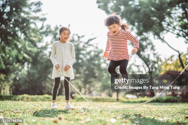 young family jumping rope joyfully on the lawn - jump rope stockfoto's en -beelden