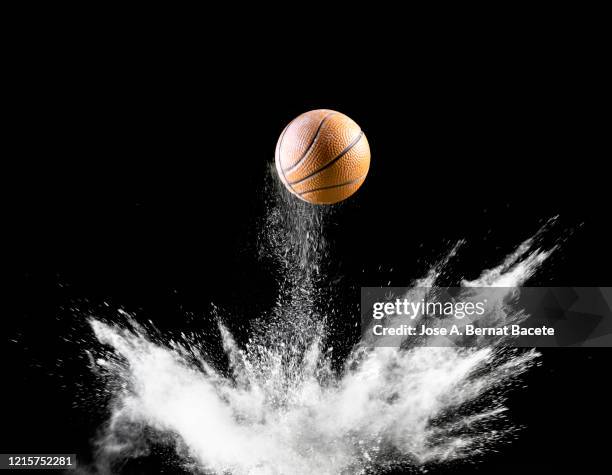 impact and rebound of a ball of basketball on a surface of land and powder on a black background - ballon rebond stock-fotos und bilder
