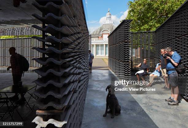 Inside pavilion looking to Serpentine Gallery with people and dog. Serpentine Summer Pavilion 2018, London, United Kingdom. Architect: Frida...