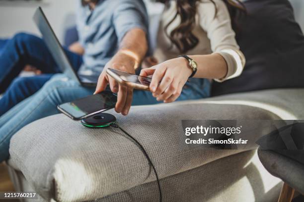 couple placing smart phone on charger - wireless charger stock pictures, royalty-free photos & images