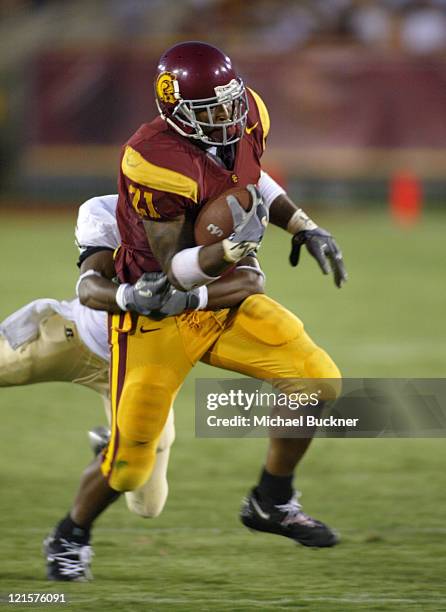 Tailback LenDale White of the University of Southern California fights the tackle of cornerback Robert Herbert of Colorado State University during...