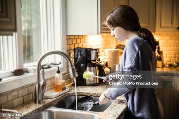 teenage girl doing dishes in kitchen - afwas doen stockfoto's en -beelden
