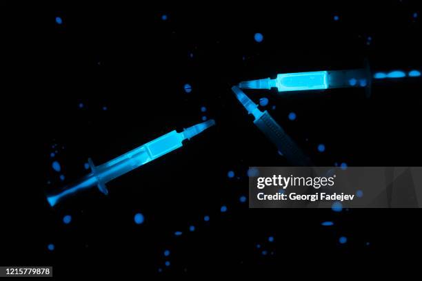 fluorescent syringe on black background, antidote. covid 19 concept. - squirt stockfoto's en -beelden