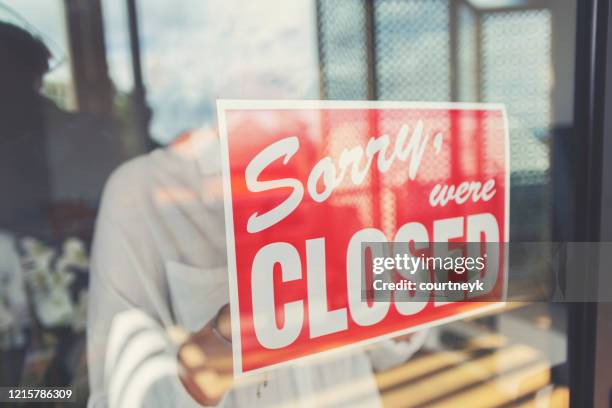 store owner putting up a closed sign in the window. - closed sign stock pictures, royalty-free photos & images