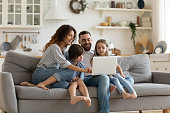 Happy family with kids sit on couch using laptop