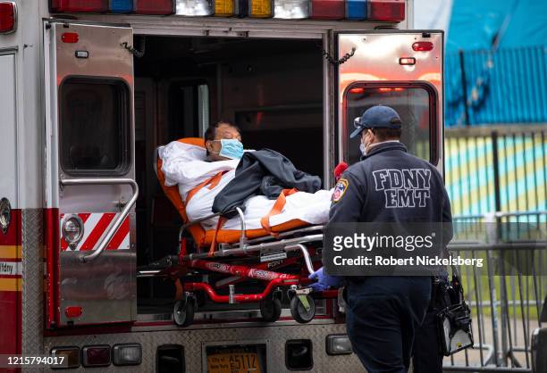 Two members of the Fire Department of New York"u2019s Emergency Medical Team wheel in a patient with potentially fatal coronavirus to the Elmhurst...