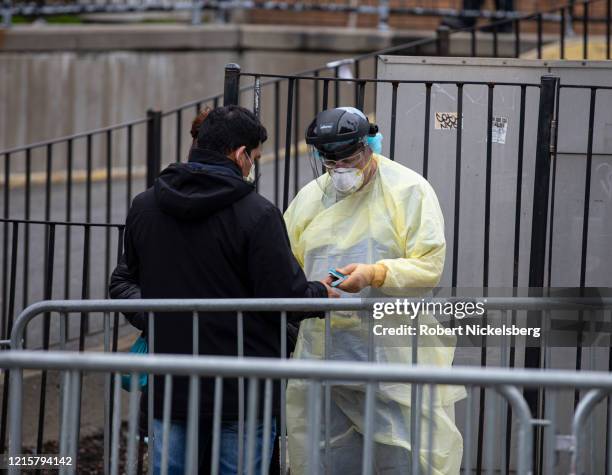 Medical technician, right, checks a patient"u2019s temperature before they enter the Emergency Room with symptoms of possible coronavirus at the...