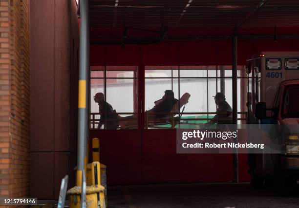 Two members of the Fire Department of New Yorks Emergency Medical Team wheel in a patient with potentially fatal coronavirus to the Elmhurst Hospital...