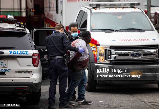 Two officers of the New York Police Department escort a handcuffed man under arrest to the Emergency Room at the Elmhurst Hospital Center in the...